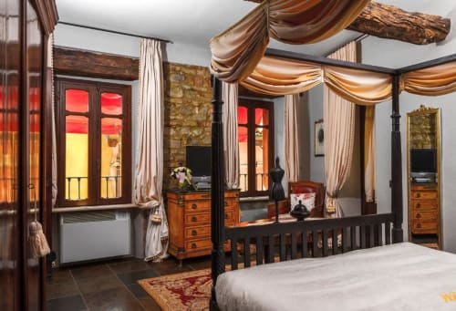 Camera da letto lussuosa con letto a baldacchino con drappeggi, arredi in legno e porte-finestre nell'appartamento Dimora i Manichei