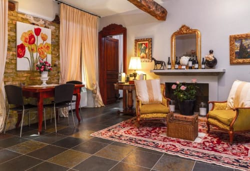 Elegant living room at Dimora i Manichei in Monforte d'Alba with golden chairs, fireplace, and classic Italian decor