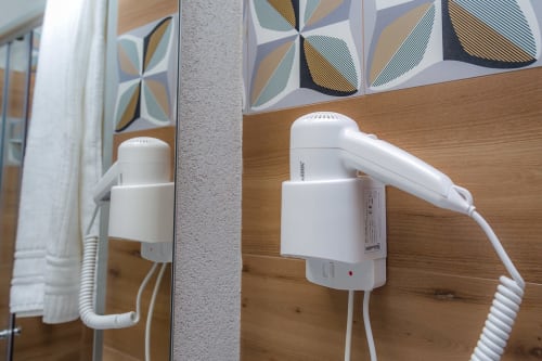 Asciugacapelli bianchi a parete con cavi arrotolati nella Nerello Room di Macramè Fazello, hotel Sciacca con opere d'arte geometrica