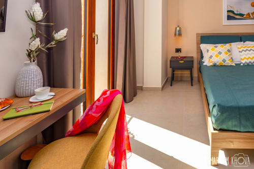Camera Nerello presso Macramè Fazello a Sciacca con letto turchese, scrivania in legno con fiori bianchi e illuminazione calda