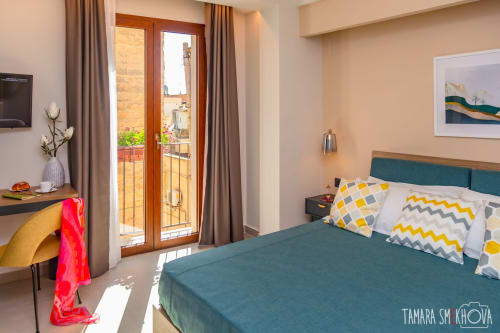 Camera Nerello presso Macramè Fazello a Sciacca con letto turchese, dettagli gialli, balcone con vista su landmark, scrivania e design moderno