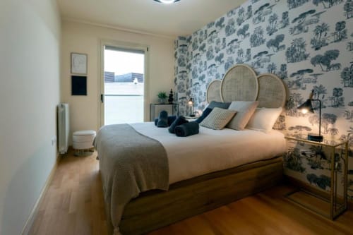 Moderno dormitorio en La Quinta Esencia, Burgos con papel tapiz de árboles, suelo de madera y vistas a la ciudad