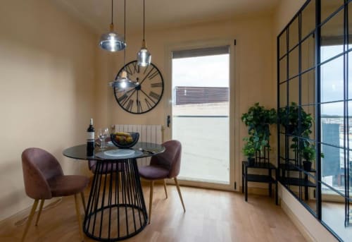 Comedor moderno en el apartamento La Quinta Esencia, Burgos con mesa redonda, sillas burdeos, lámparas colgantes y punto de referencia