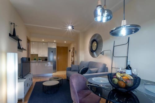 Sala de estar moderna en Burgos con sofá gris, comedor, lámparas colgantes y cocina abierta