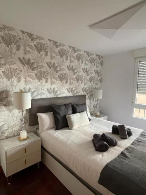 Dormitorio moderno en Five Senses by Unique Rooms, Burgos con papel tapiz botánico, cama tapizada gris y vistas a la ciudad