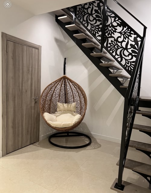 Fauteuil suspendu tressé avec coussins crème sous l'escalier moderne aux Gîtes Les Camelias 71, Oslon