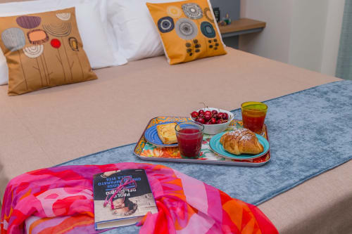 Vassoio colazione sul letto delle camere Macramè Fazello a Sciacca con pasticcini, ciliegie, succo e cuscini colorati