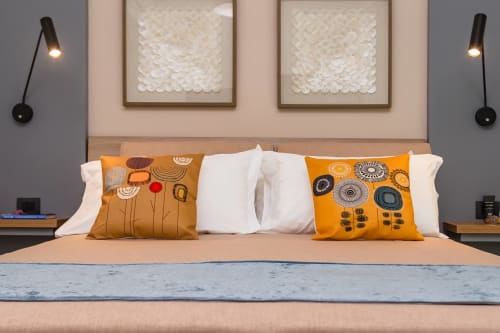 Camera Cricket presso Macramè Fazello a Sciacca con letto dai cuscini arancioni decorati, biancheria bianca, applique murali