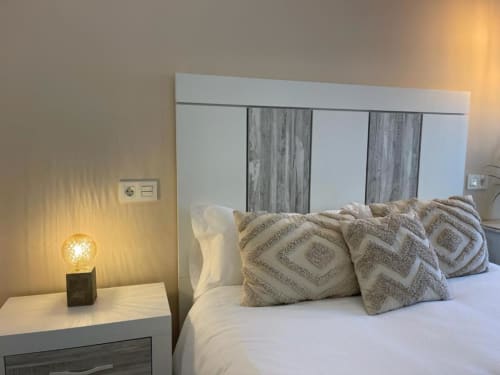 Dormitorio moderno en Valeria's Corner, Burgos con cama blanca, almohadas estampadas y lámpara de noche