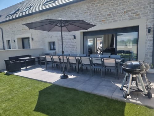 Patio moderne avec table à manger, parasol noir et barbecue aux Gîtes Les Camélias 71 à Oslon, France