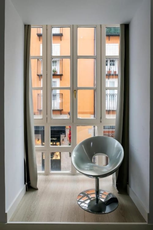 Silla moderna junto a ventanales que dan al patio de Burgos en el apartamento Spacio Menina
