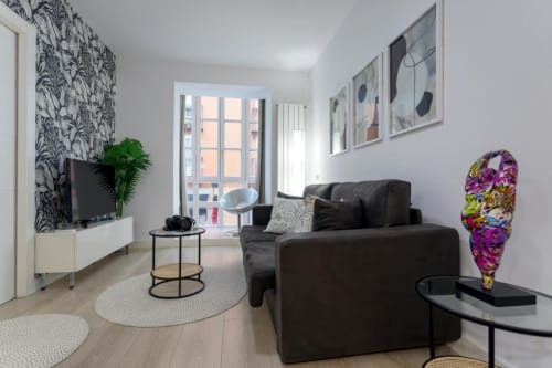 Elegante sala de estar en el apartamento Spacio Menina, Burgos con sofá negro, balcón, televisor de pantalla plana y decoración contemporánea