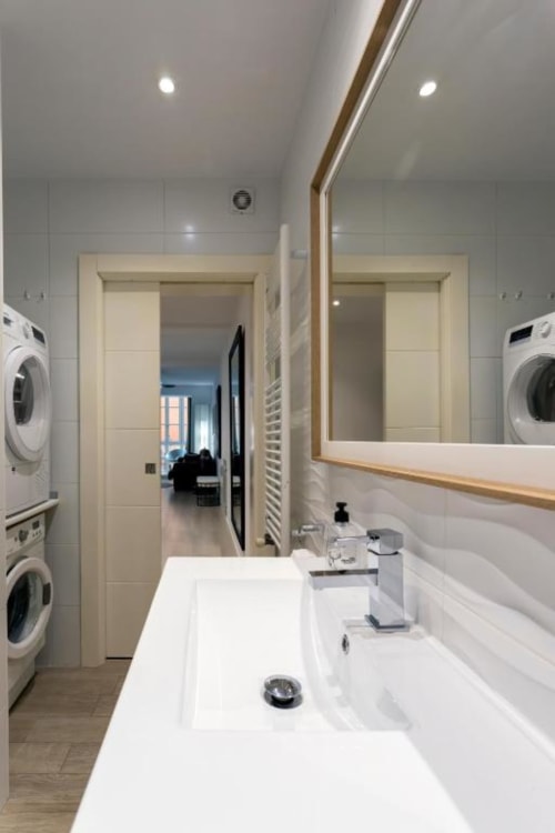 Baño moderno del apartamento Spacio Menina en Burgos con lavabo blanco, espejo, lavadoras y bañera