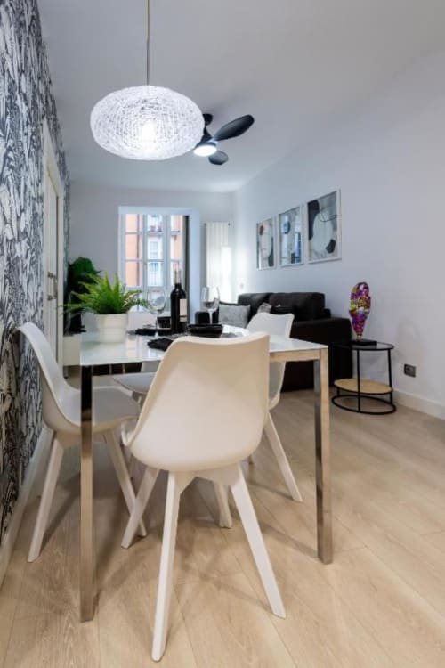 Comedor moderno con sillas blancas en mesa de madera en apartamento Spacio Menina, Burgos, con lámpara colgante contemporánea