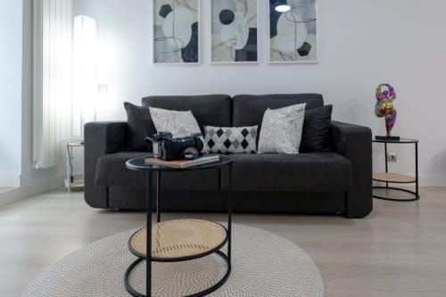 Sala de estar moderna en Spacio Menina, Burgos con sofá negro, mesa auxiliar redonda y arte contemporáneo en la pared