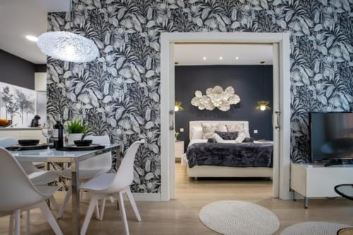 Apartamento moderno en Burgos con papel pintado tropical, zona de comedor y dormitorio visible a través de la puerta