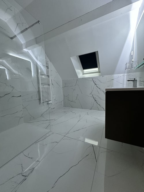 Salle de bain moderne aux Gîtes Les Camélias 71 : carrelage marbre, douche italienne, sèche-serviettes chauffant et fenêtre de toit