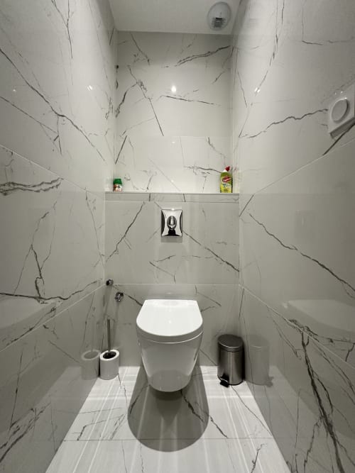 Salle de bain moderne aux Gîtes Les Camélias 71 avec murs effet marbre, toilettes blanches et accessoires chromés