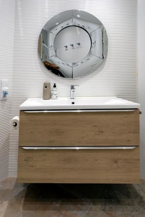 Tocador de baño moderno con gavetas de madera y lavamanos blanco en apartamento Audrey, Burgos