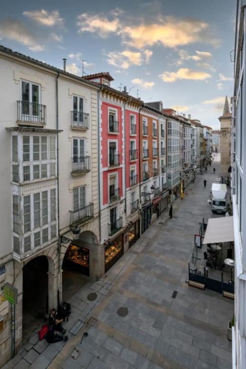 Calle histórica de Burgos con edificios coloridos y apartamento de fachada roja, vista de la ciudad desde Audrey by Unique Rooms