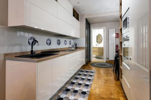 Cocina moderna blanca en apartamento Audrey, Burgos con encimeras de madera, placa de cocción negra y baldosas hexagonales