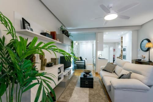 Sala de estar moderna en Audrey by Unique Rooms en Burgos con sofá crema, plantas, televisor y vistas a la ciudad