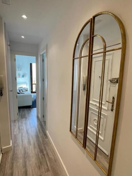 Pasillo moderno en apartamento Urban Home, Burgos con espejo dorado arqueado y puertas blancas hacia dormitorio