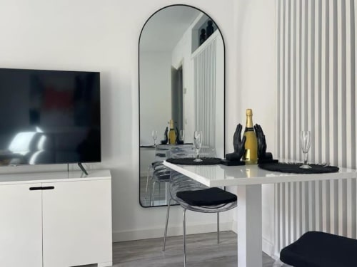 Comedor moderno en Urban Home Burgos con mesa blanca, espejo, botella de champagne y decoración minimalista