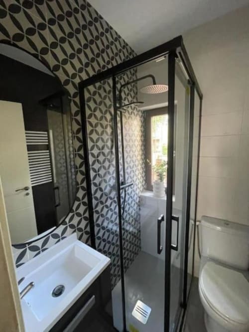 Baño moderno en apartamento Urban Home con cabina de ducha de marco negro, azulejos decorativos y accesorios blancos en Burgos