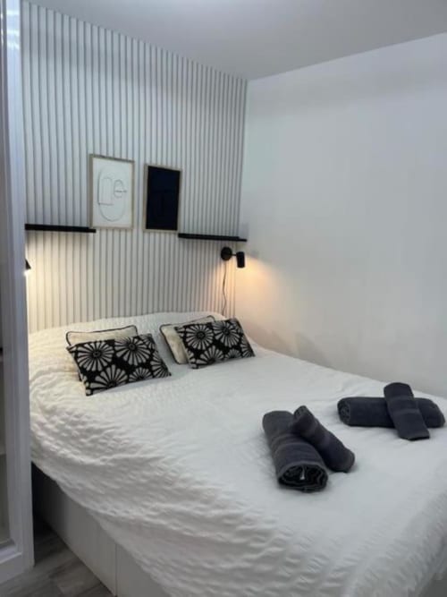 Dormitorio moderno en Urban Home by Unique Rooms en Burgos con cama blanca, almohadas con patrón negro y pared contemporánea