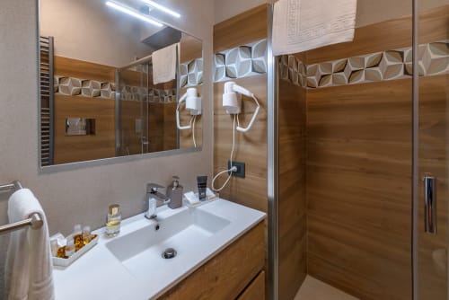 Moderno bagno nella Camera Cricket di Macramè Fazello, Sciacca con pannelli in legno, specchio illuminato e doccia