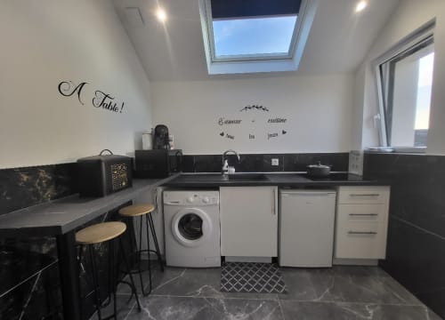 Cuisine moderne en noir et blanc aux Gîtes Les Camélias 71 à Oslon avec puits de lumière, lave-linge et décoration murale française