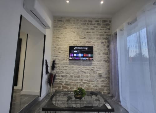Chambre moderne avec mur en briques, téléviseur mural et plantes décoratives aux Gites Les Camelias 71, Oslon