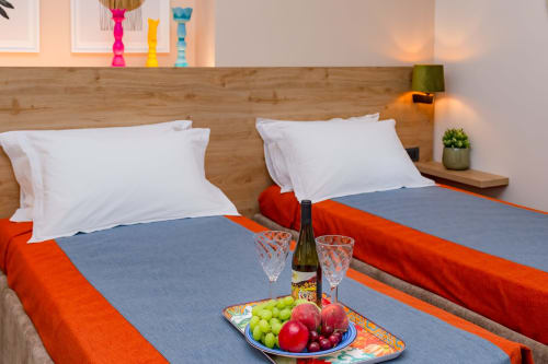 Camera moderna a Macramè Fazello a Sciacca con bottiglie decorative colorate, cuscini bianchi, frutta fresca e vino sul letto