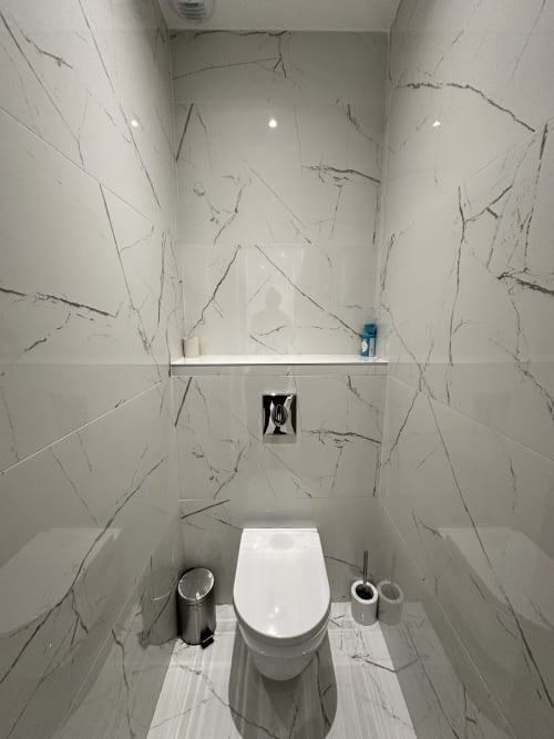 Salle de bain moderne aux carreaux imitation marbre, toilettes et étagère blanche aux Gîtes Les Camélias 71, Oslon France