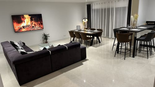 Séjour moderne ouvert aux Gites Les Camelias 71 avec canapé noir, table à manger et bar cuisine
