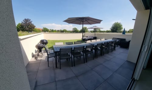 Terrasse moderne sur le toit des Gites Les Camelias 71 à Oslon avec table de dining, chaises, parasols et barbecue