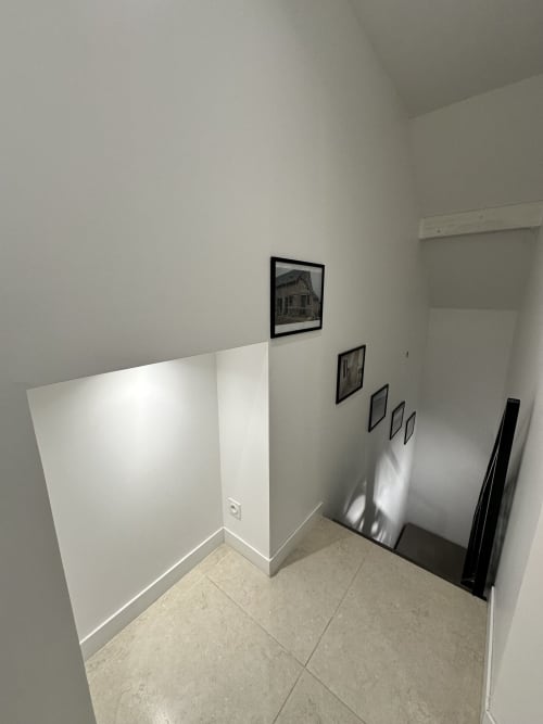 Chambre minimaliste aux Gîtes Les Camelias 71 : murs blancs, tableaux encadrés et carrelage