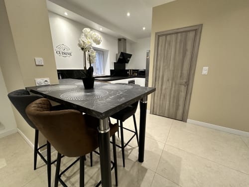Cuisine-salle à manger moderne aux Gites Les Camelias 71 avec table noire, chaise marron et orchidée blanche