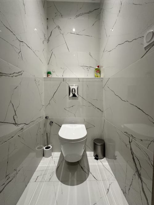 Salle de bain moderne aux carrelages effet marbre et toilettes blancs épurés aux Gîtes Les Camélias 71, Oslon