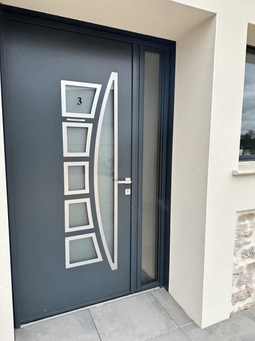 Porte d'entrée gris foncé moderne avec design géométrique blanc aux Gites Les Camelias 71 à Oslon, France