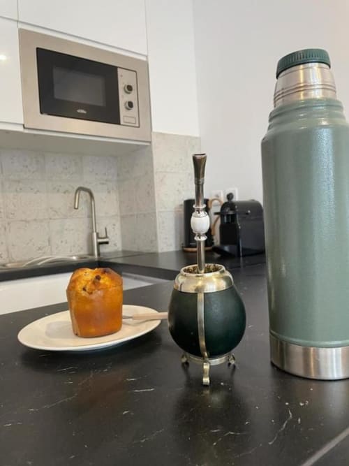 Comptoir de cuisine moderne à l'Appart Hôtel Panambi avec pâtisserie, tasse de maté, thermos et micro-ondes