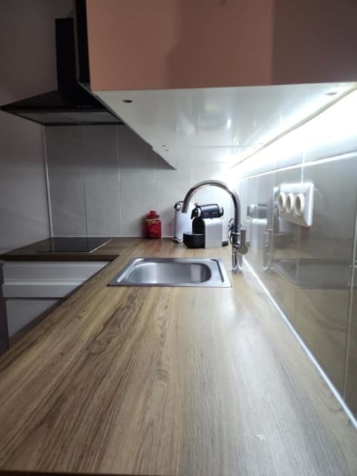 Cuisine moderne avec plan de travail en bois, évier inox et hotte noire à l'Appart Hôtel Panambi Chevilly-Larue