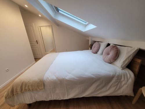 Chambre moderne en mezzanine à l'Appart Hôtel Panambi avec lit queen, puits de lumière et coussins mauve à Chevilly-Larue