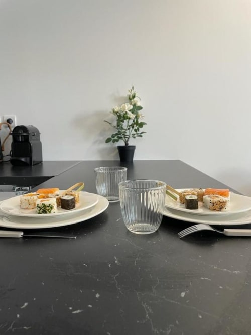 Élégant dîner de sushi présenté pour deux à l'Appart Hôtel Panambi, Chevilly-Larue, avec table minimaliste et fleurs blanches.