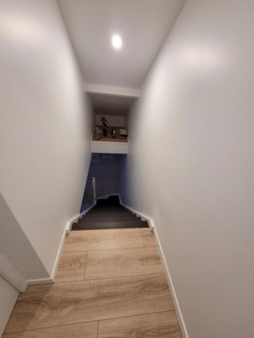 Couloir étroit aux murs blancs, parquet en bois et escalier descendant à l'Appart Hôtel Panambi