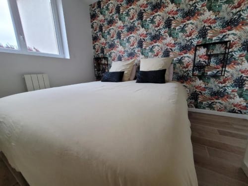 Dormitori modern a l'Appart Hôtel Panambi a Chevilly-Larue amb roba de llit blanca, paper pintat floral i finestra amb vistes a la ciutat