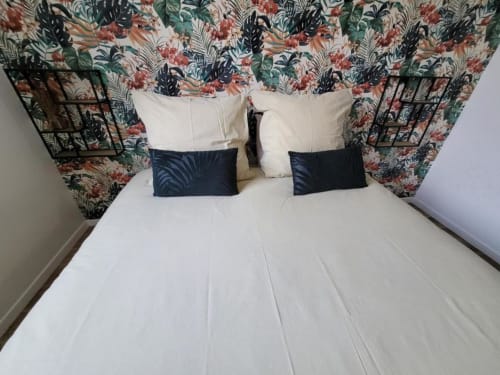Lit avec tête de lit floral à l'Appart Hôtel Panambi à Chevilly-Larue, draps blancs et oreillers bleu marine