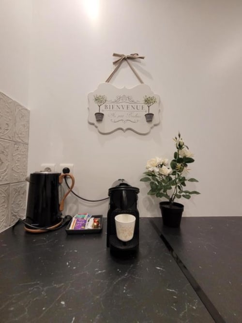 Coin kitchenette à l'Appart Hôtel Panambi avec cafetière, bouilloire, fleurs blanches et pancarte de bienvenue