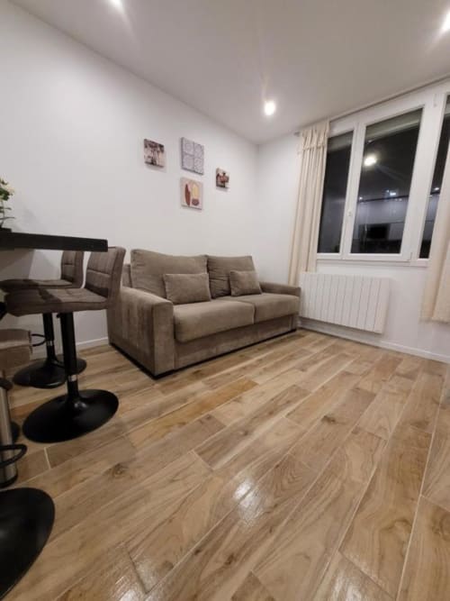 Séjour moderne de l'Appart Hôtel Panambi à Chevilly-Larue avec canapé beige, parquet et vue sur la ville